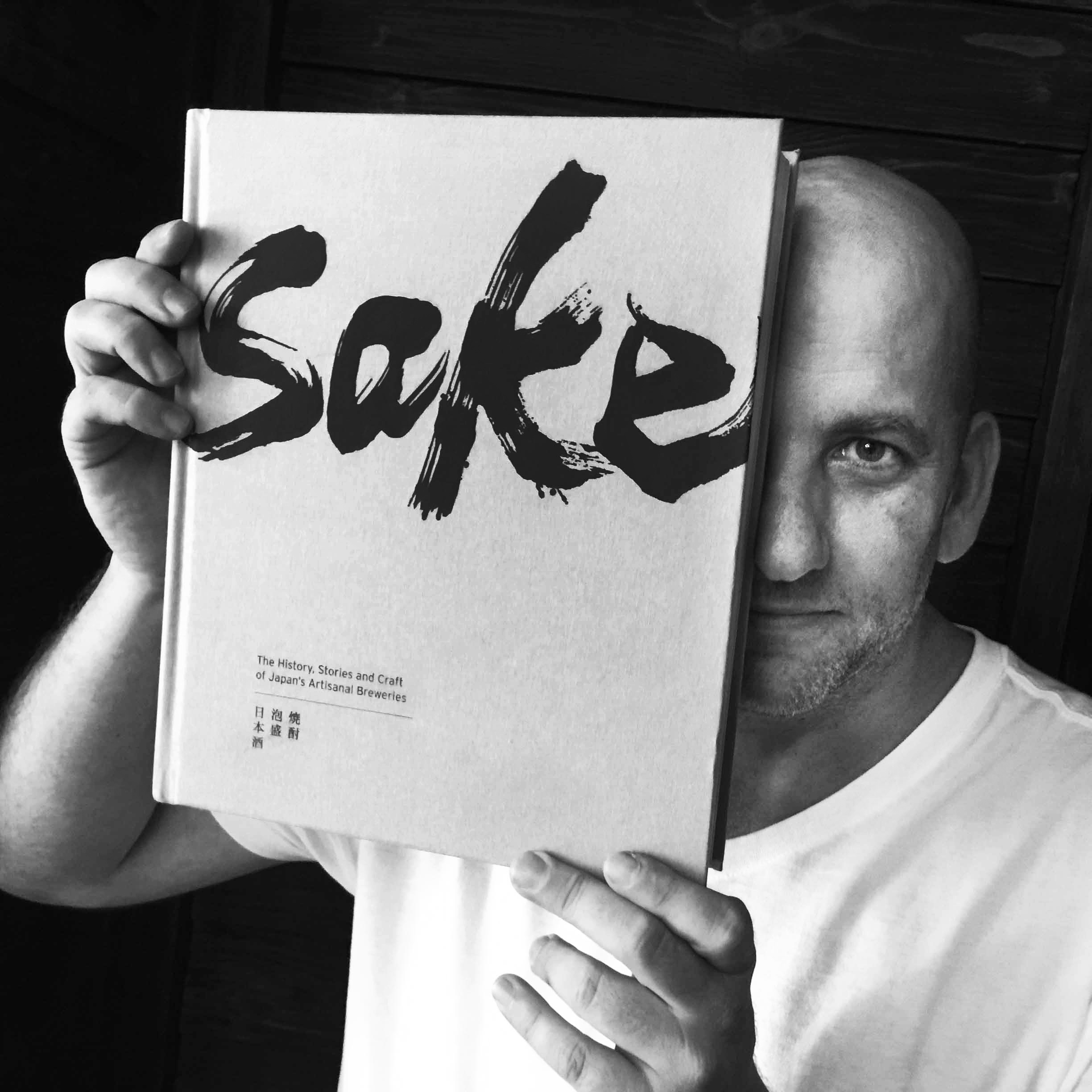 Jason Michael Lang holding a copy of Sake: The History, Stories, and Craft of Japan's Artisanal Breweries