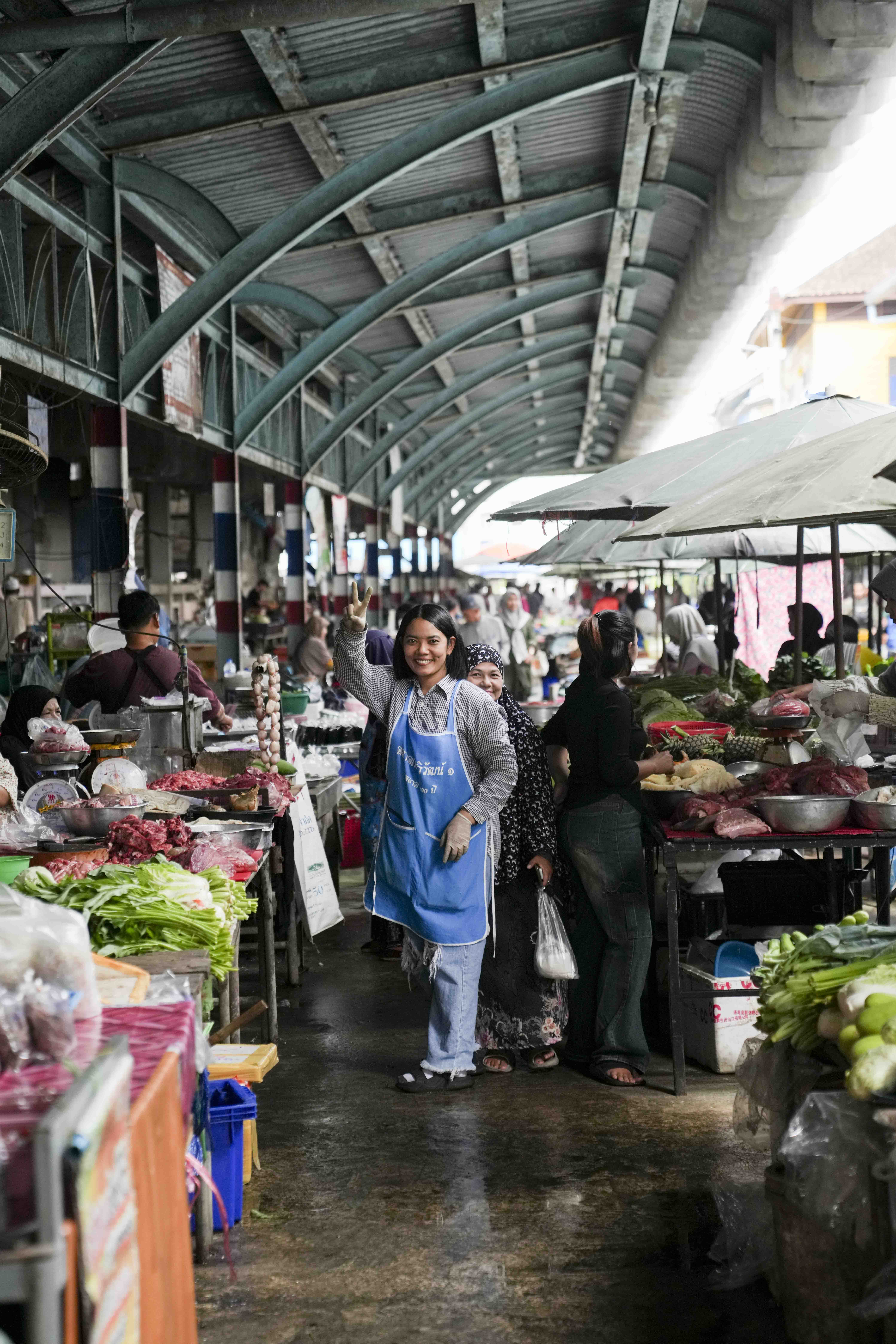 Bangkok morning market vendor in blue apron amid the stalls