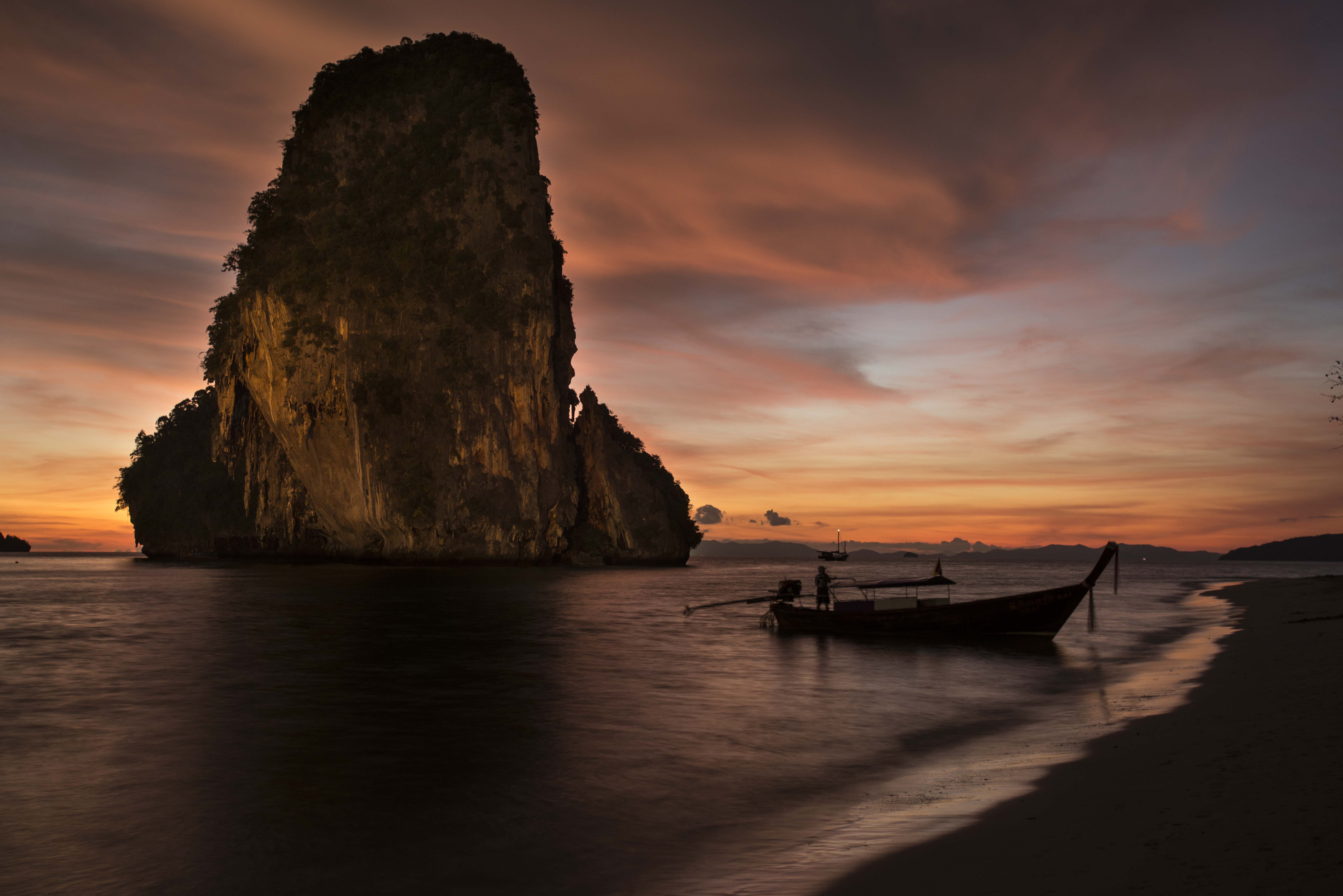 Longtail boat at dusk, Krabi — limestone karst silhouetted against evening sky